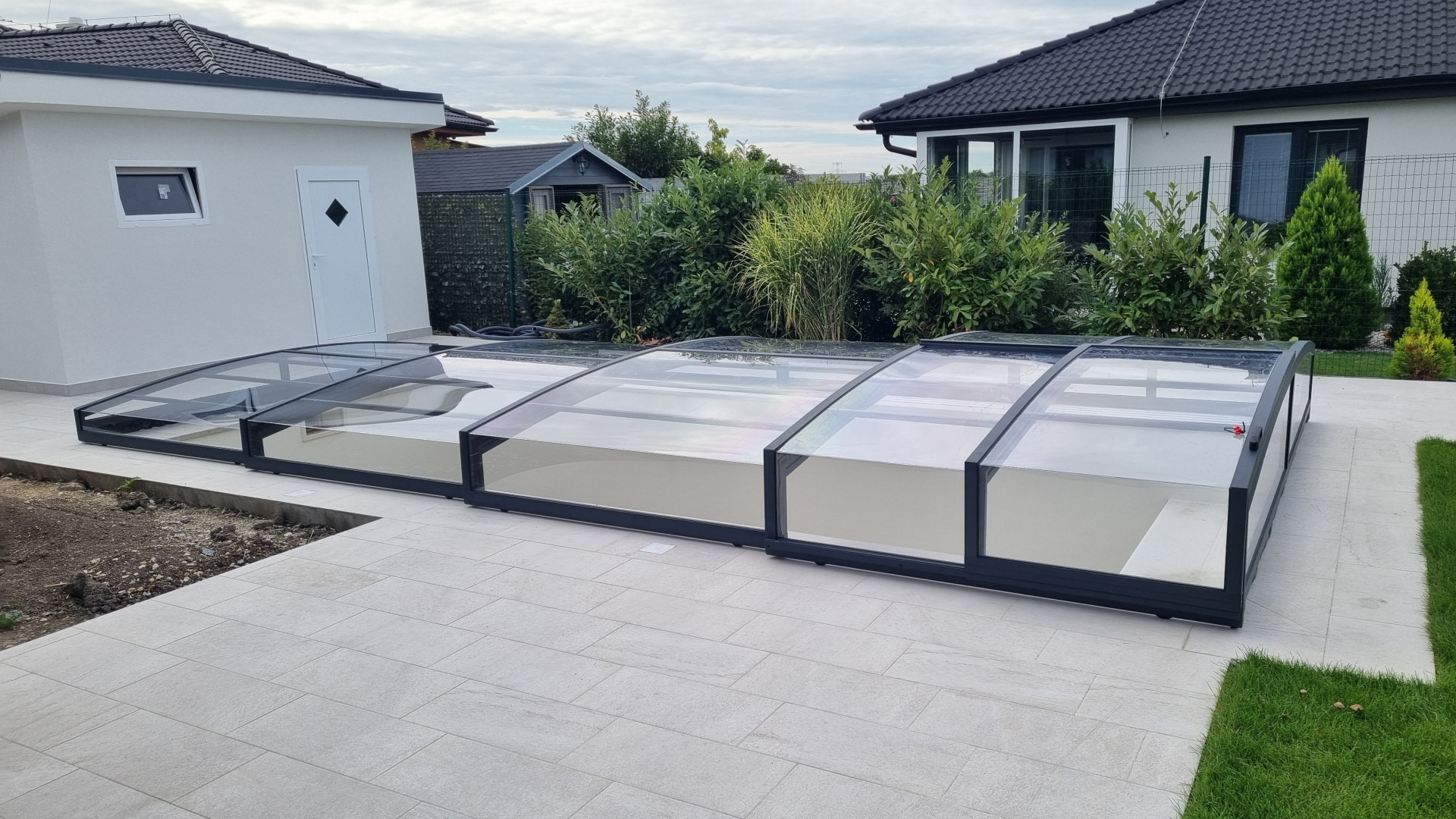 A modern, low-profile pool enclosure with black trim on the deck of a single-family home