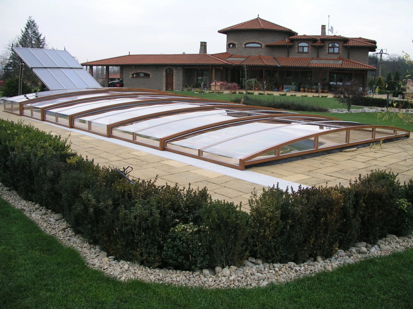 A low-profile pool enclosure with a wood-grain finish in the garden of a single-family home