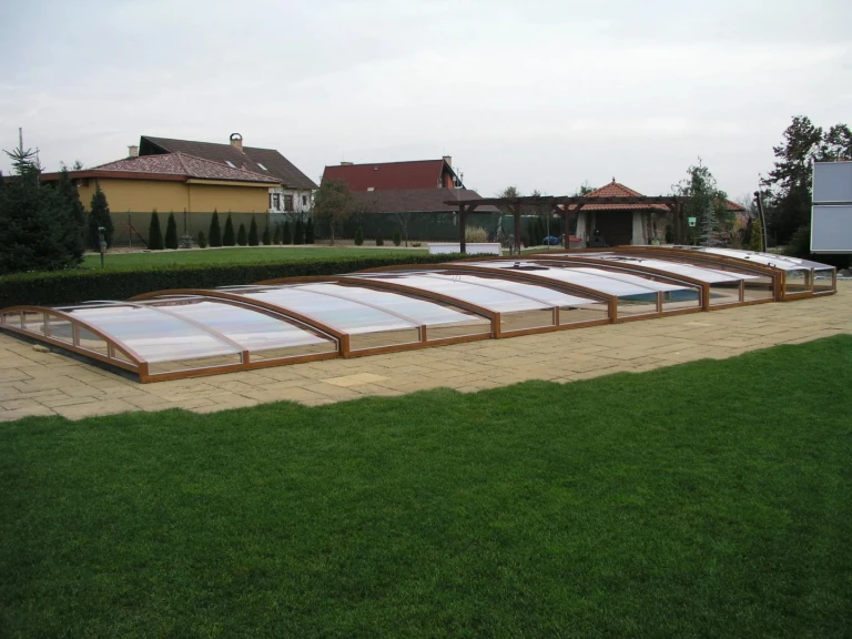 A low-profile STAR pool enclosure with a wood-grain finish in the garden of a single-family home