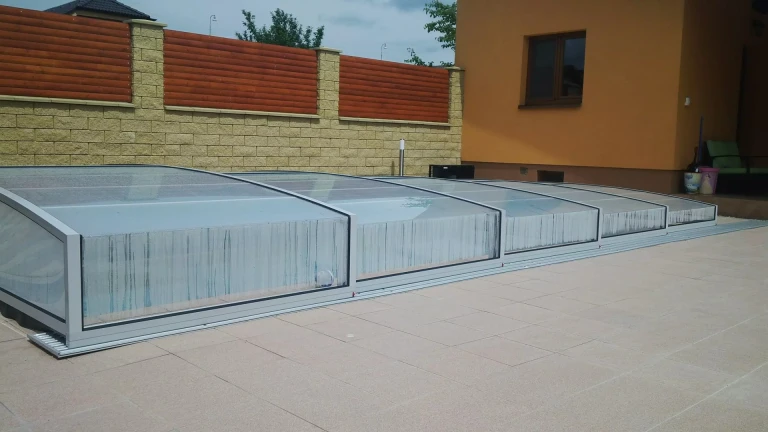 Modern, low-profile pool enclosure with transparent panels in Trenčianska Teple
