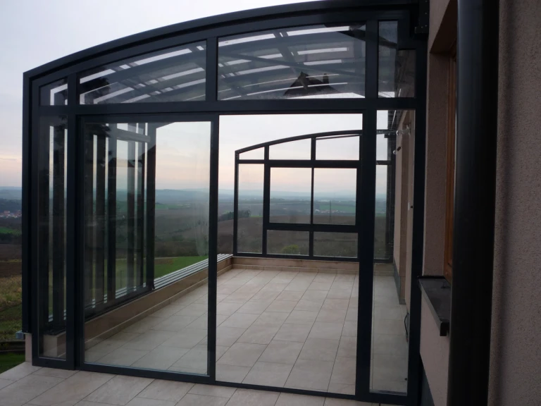 A modern glass-enclosed terrace with a view of the countryside
