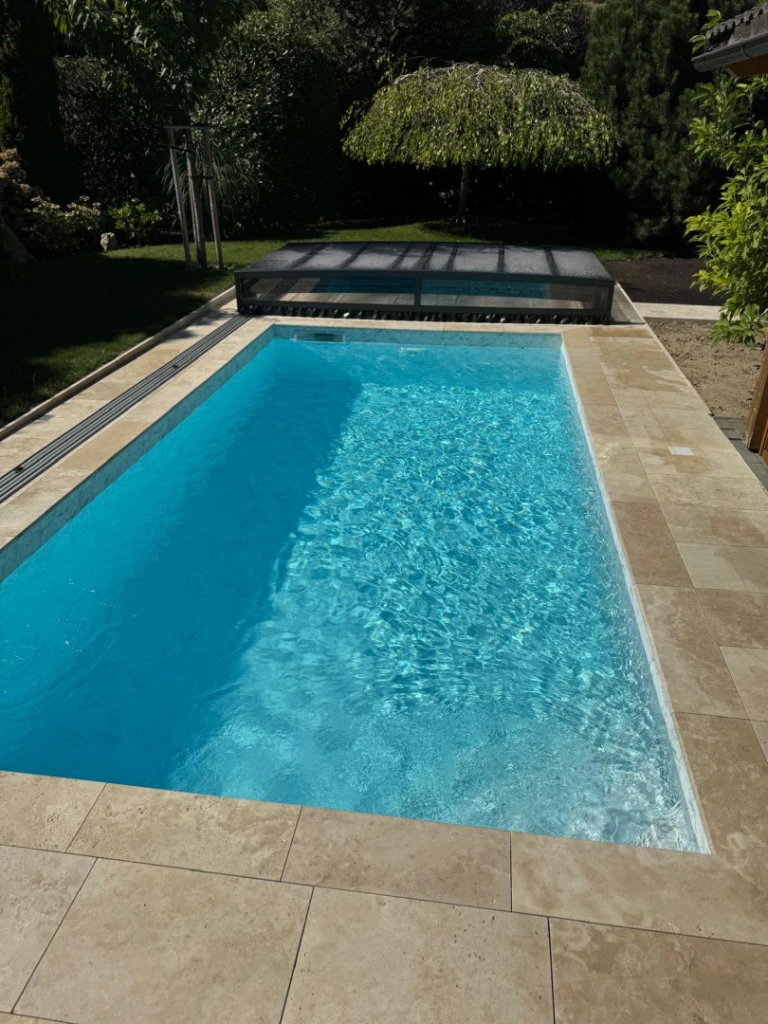 A modern pool with crystal-clear water and a retractable low roof in the garden