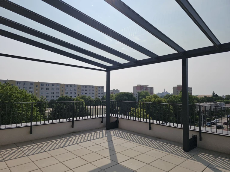 A modern aluminum pergola with a glass roof on a spacious terrace overlooking the city.