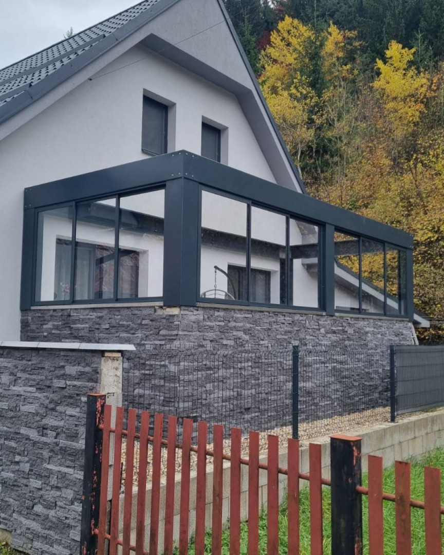 Modern terrace glazing on a single-family home with dark frames and stone cladding