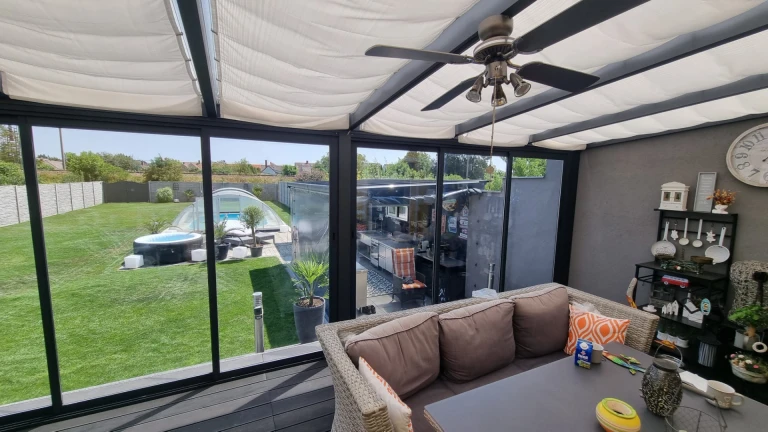 The interior of a modern aluminum sunroom overlooking the backyard and the pool