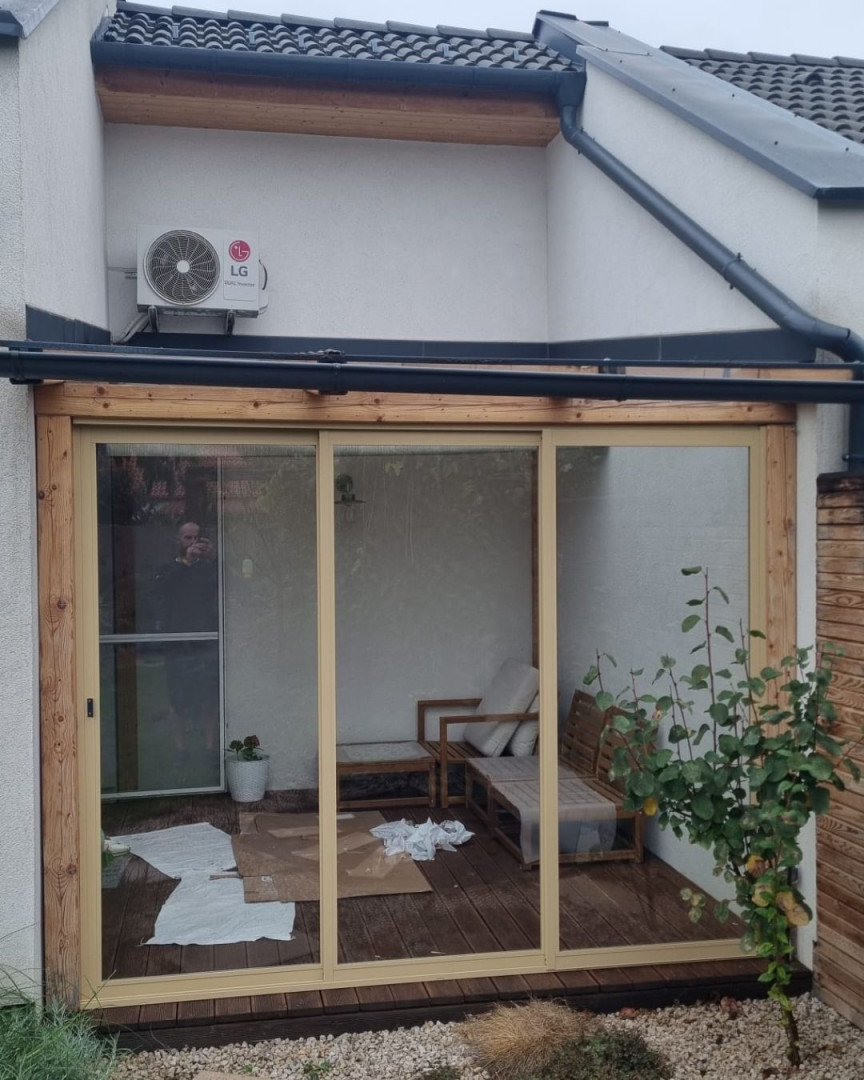 Modern sliding glass doors on the patio with a wooden frame and outdoor furniture.