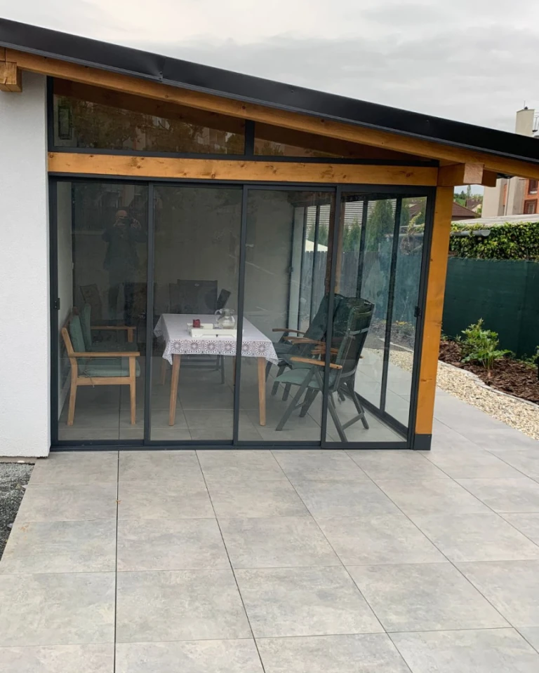 Modern sliding glass doors on the patio with a wooden frame and outdoor seating.