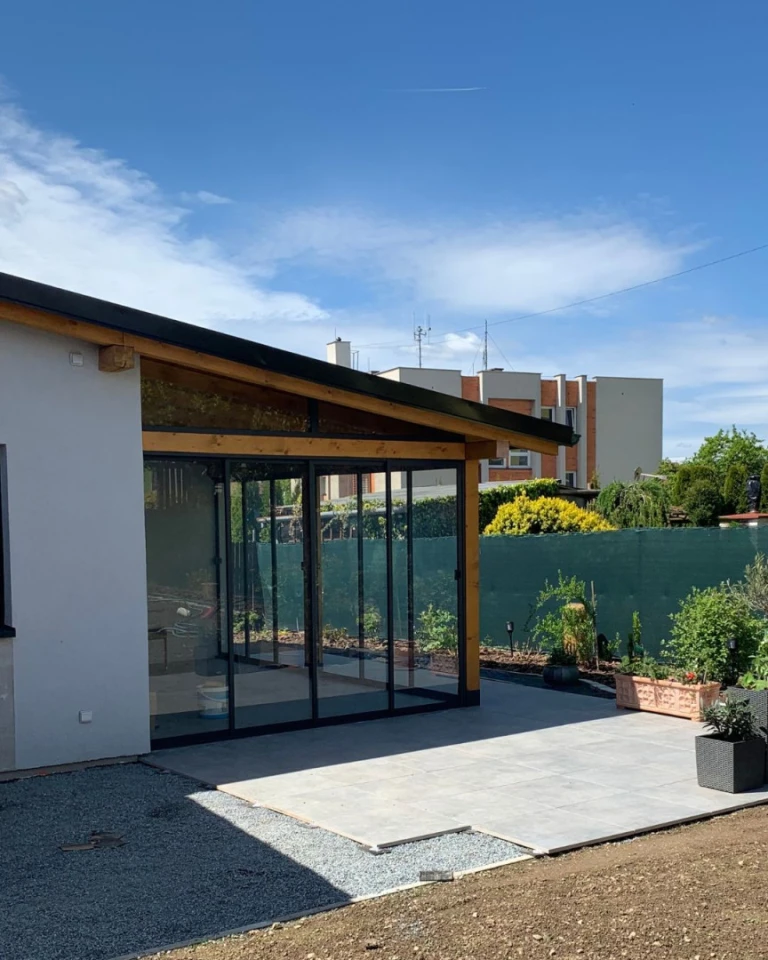 Modern terrace glazing with a sliding system and a wooden frame attached to a single-family home.