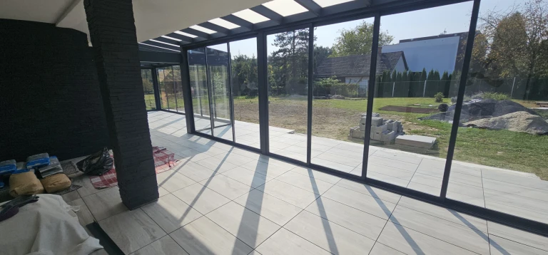 A modern, glass-enclosed sunroom overlooking the courtyard during construction