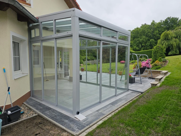 A modern, glass-enclosed "Robust" sunroom with an aluminum frame attached to a single-family home